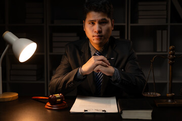 Asian male lawyer working in law office with hammer and scale and laptop, contract concept legal...