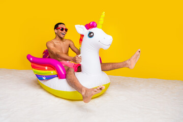 Full length photo of funky impressed masculine guy riding unicorn buoy empty space isolated yellow color background © deagreez
