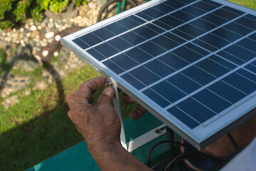 A man mounting a small 50 watt Polycrystalline solar panel on the eaves of a roof of a bungalow...