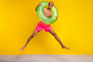 Full length photo of funky excited masculine guy jumping high having fun enjoying vacation isolated...