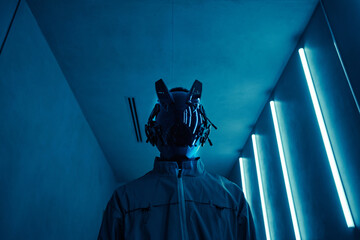 Portrait of person wearing cyberpunk robot mask in blue neon light, copy space
