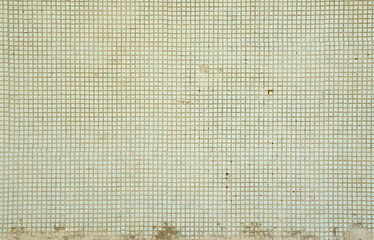 The texture of the old wall, decorated with a lot of square small tiles. Wall in the style of...