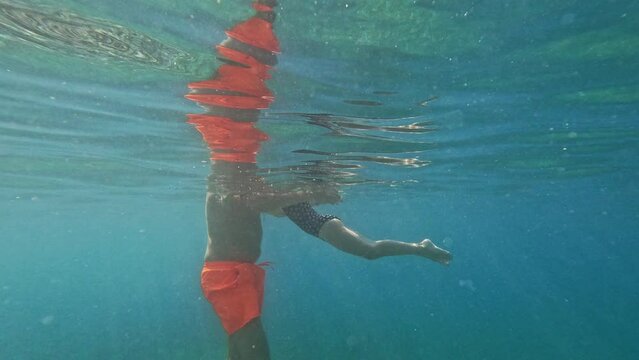 Dad teaches his daughter to swim in the sea. Underwater shooting.