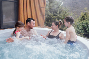 Happy family with two small children have fun in the jacuzzi