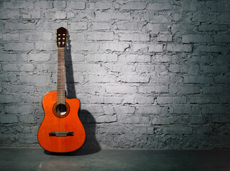 Fototapeta na wymiar Acoustic guitar leaning on grungy wall