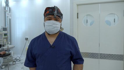 Fototapeta na wymiar Medical doctor with a binocular magnifier in a mask. Action. Background of an operating theatre.