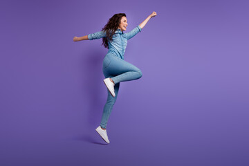 Full size profile portrait of overjoyed girl jump raise fist flying empty space isolated on purple color background - obrazy, fototapety, plakaty