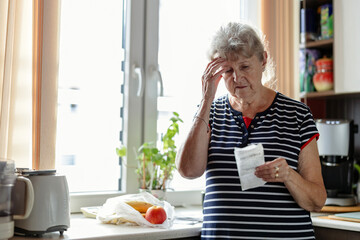 Fototapeta na wymiar Senior woman going through her receipts at home after buying groceries 