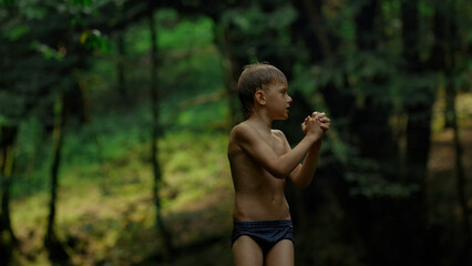 Caucasian boy Mowgli enjoys nature, wet after swimming. Creative. Boy child in swimwear with green...
