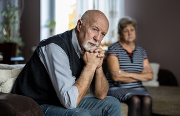 Senior couple sitting on sofa at home having a relationship problems
