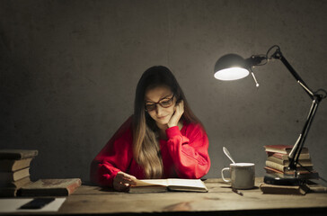 young woman studies with the light of a lamp