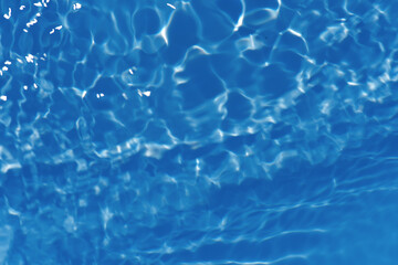 Blue water with ripples on the surface. Defocus blurred transparent white-black colored clear calm water surface texture with splash and bubbles. Water waves with shining pattern texture background.