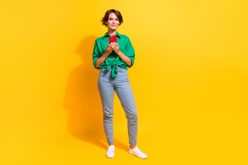 Fototapeta na wymiar Full length photo of positive cute lady wear green shirt chatting instagram twitter telegram facebook isolated yellow color background
