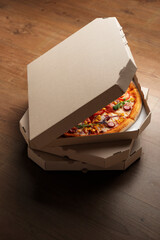 Pizza in open carton box on natural wooden table high angle view with copy-space