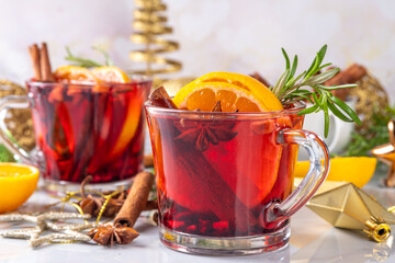 Traditional Christmas aromatic mulled wine cocktail, red wine grog tea drink with spices, cinnamon, orange and rosemary sprig, on Christmas New Year decorated wooden cozy background