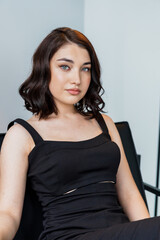 Portrait of a young beautiful girl in a black dress on a white background