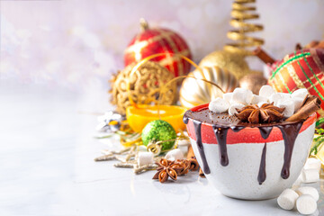 Winter aromatic hot chocolate cup with Christmas background. Mug of dark hot cocoa drink with cinnamon, anise, spices and marshmallow, on cozy Christmas and New Year holiday decorated background 