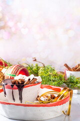 Winter aromatic hot chocolate cup with Christmas background. Mug of dark hot cocoa drink with cinnamon, anise, spices and marshmallow, on cozy Christmas and New Year holiday decorated background 