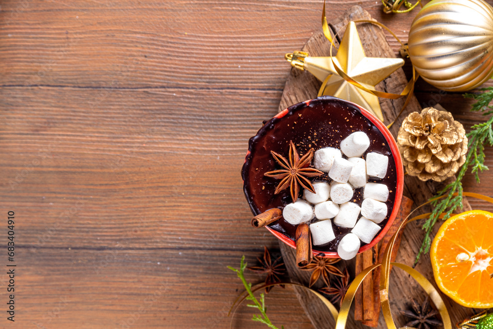 Wall mural Winter aromatic hot chocolate cup with Christmas background. Mug of dark hot cocoa drink with cinnamon, anise, spices and marshmallow, on cozy Christmas and New Year holiday decorated background 