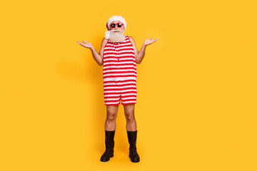 Full length photo of unsure funky senior guy christmas swimwear hat shrugging shoulders empty space...