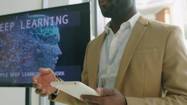 Corporate worker using display and digital tablet pitching new ideas for his co-workers during meeting