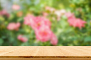 Empty wood table top with blur rose garden background for product display