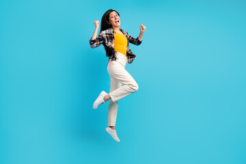 Fototapeta na wymiar Full length body size view of nice girl jumping having fun rising hands up isolated on blue color background