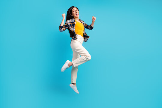 Full length body size view of nice girl jumping having fun rising hands up isolated on blue color background