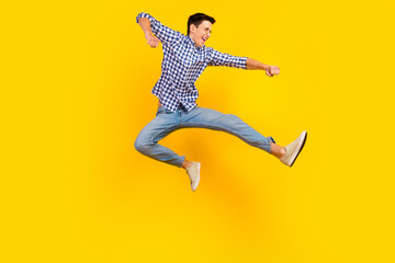 Fototapeta na wymiar Full length portrait of excited young man in shirt jumping while celebrating isolated over bright color background