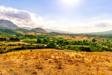 panoramic farmland view of yellow field with sceniv valley , mountains and amazing cloudt sunset