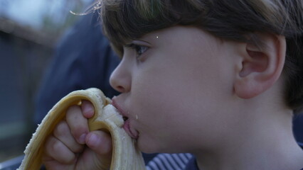 Close-Up of Small Boy Enjoying a Banana, Healthy Snack While Riding a Miniature Train at Railroad Park