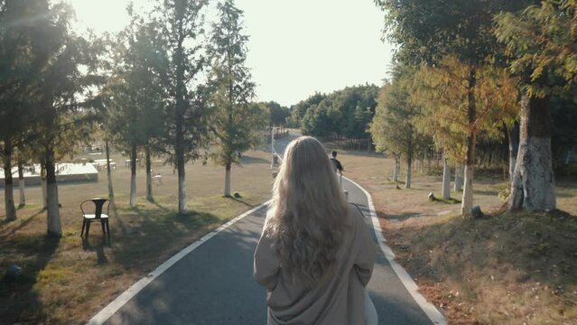 A Blond Hair Girl in Beige Trench Coat Walking in the Park 4K