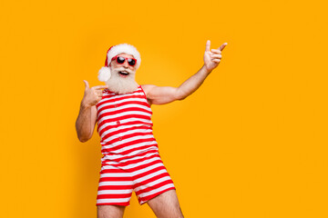 Fototapeta na wymiar Photo of crazy good mood senior guy dressed christmas swimwear dancing discotheque pointing empty space isolated yellow color background