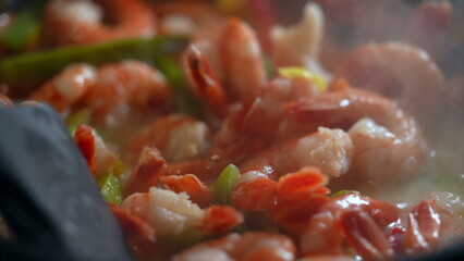Cooking shrimps and vegetables inside pan, stirring food and preparing meal macro close-up