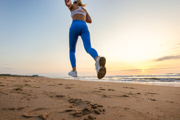 sportive woman running along beautiful sandy beach enjoying active summer near the sea