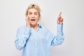 Young blond woman in casual pointing aside finger, demonstrating empty space for product or text...