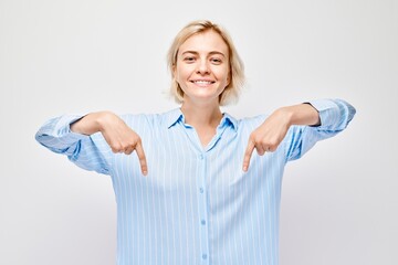 Young blond woman in casual pointing down finger, demonstrating empty space for product or text...