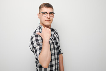 Handsome man in glasses pointing aside finger, demonstrating empty space for product or text...