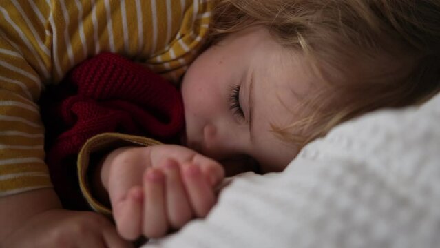 Peaceful adorable baby sleeping on a bed at home. Slumbering little child. Two year old girl sleeps peaceful at domestic room interior background. Serene dream. Cute face close up. Deep kid slumber	