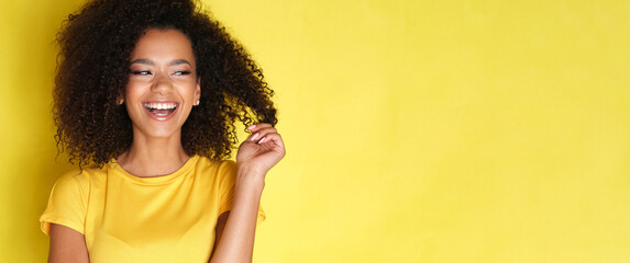 Cute female with curly hair on yellow background.