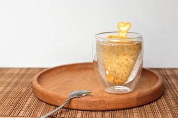 Brew iced tea on a stick in a modern transparent glass mug. Buckthorn, orange, mango fruit...