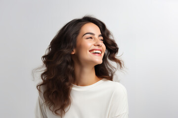 Obraz premium Happy young woman looking away with a smile while standing in a studio background