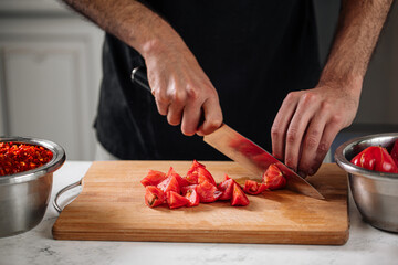 Chef cutting fresh tomatoes on wooden board preparing food