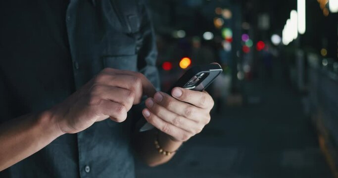 Close up male hands scrolling browsing social networks on smartphone on background of lights of night city. Scrolling social media concept. Male scroll through news feed on mobile app on smartphone.