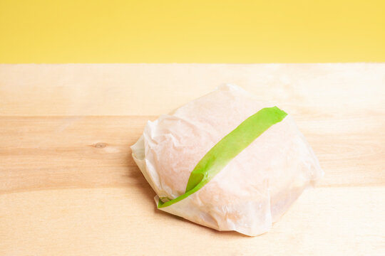 Tasty Burger On A Wooden Table, Wrapped In Paper