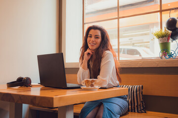 Portrait of a woman looking a the camera while she is working with her laptop