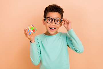 Photo of intelligent diligent astonished boy wearing trendy clothes hands holding colorful game...