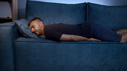 Exhausted overloaded young man in casual clothes came home after work flopped down on sofa very...