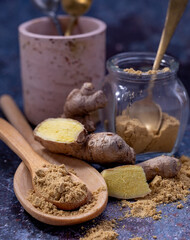 Fresh ginger root and ginger powder placed on a wooden stick, glass jar