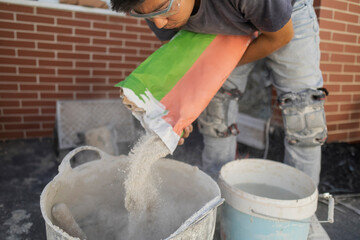 construction assistant pouring cement preparing the mixture